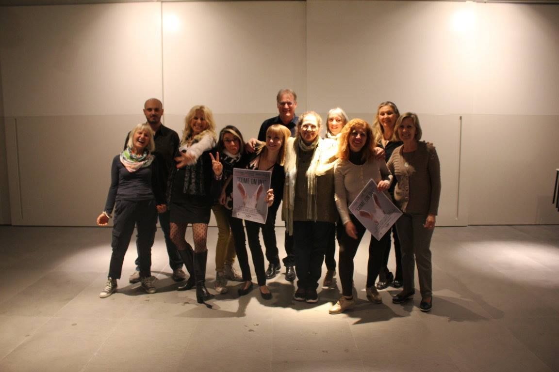 Un gruppo di adulti a fine laboratorio, sorridenti, in una sala bianca